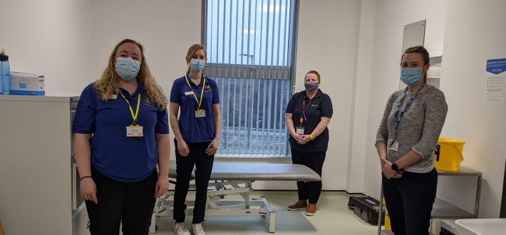 physiotherapists and staff at the advanced wellbeing research centre standing with masks on socially distanced looking at camera