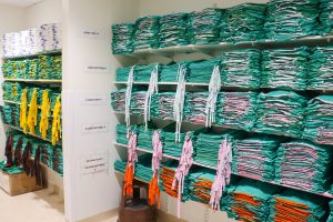 Shelves in scrub room fully-stocked with green scrubs in size order