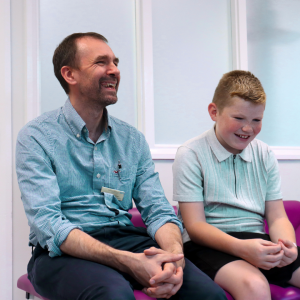 Evan sits with a member of staff at Sheffield Children's