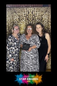 The MRI Team smile in front of a gold curtain