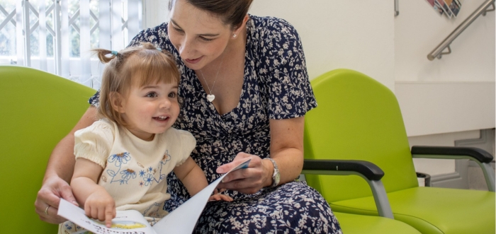 A parent and child sit in a waiting area